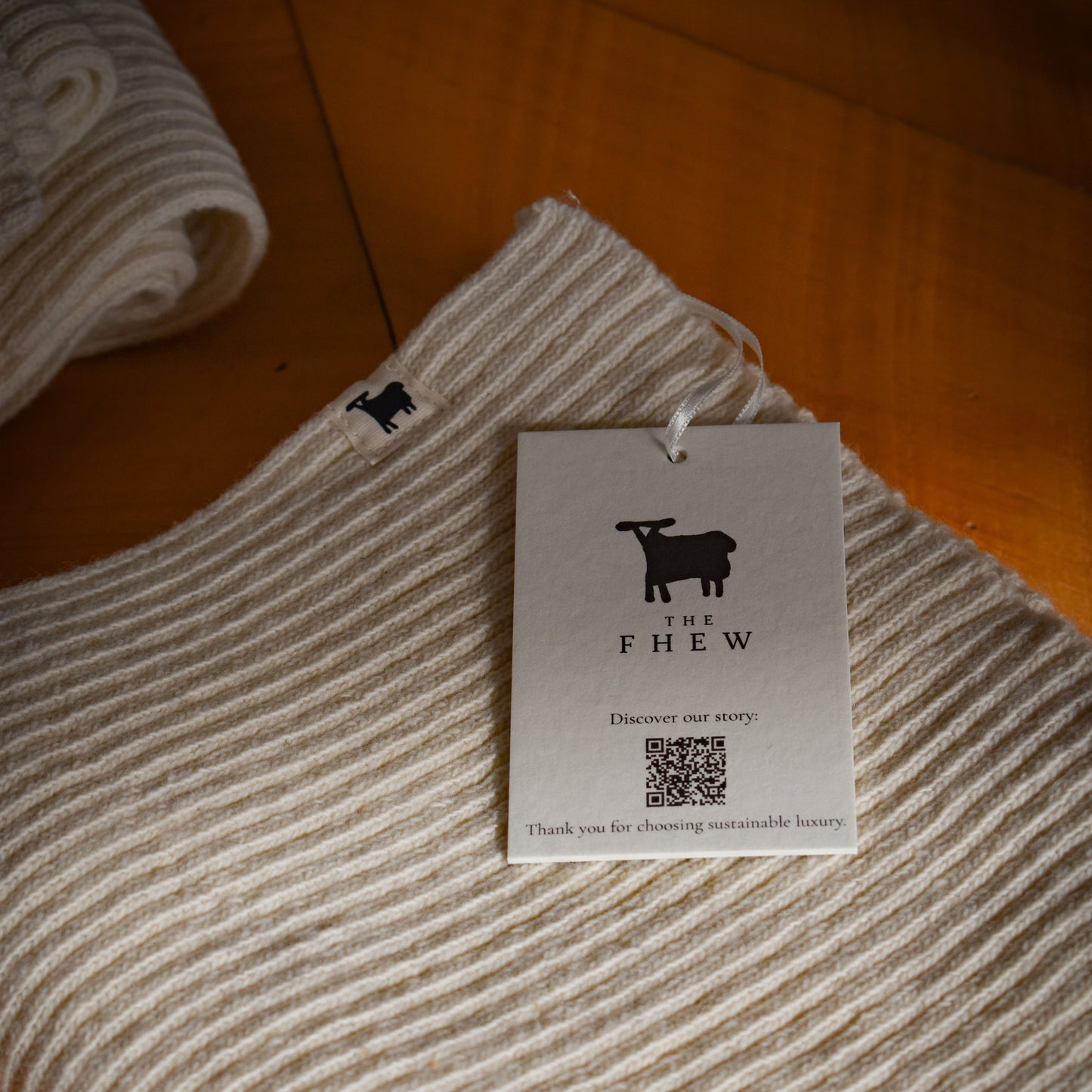 Folded beige fabric with a tag labeled 'THE FHEW' on a wooden surface