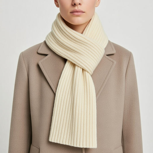 Person wearing a beige coat and cream merino wool scarf on a light gray background